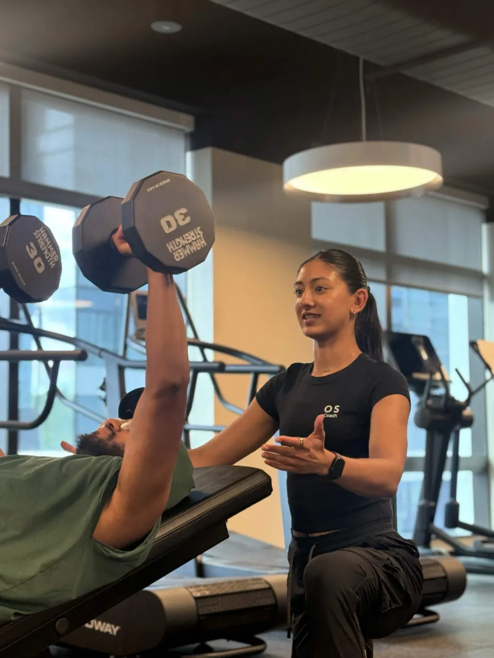 Amrit Kaur coaching a client through a dumbbell press